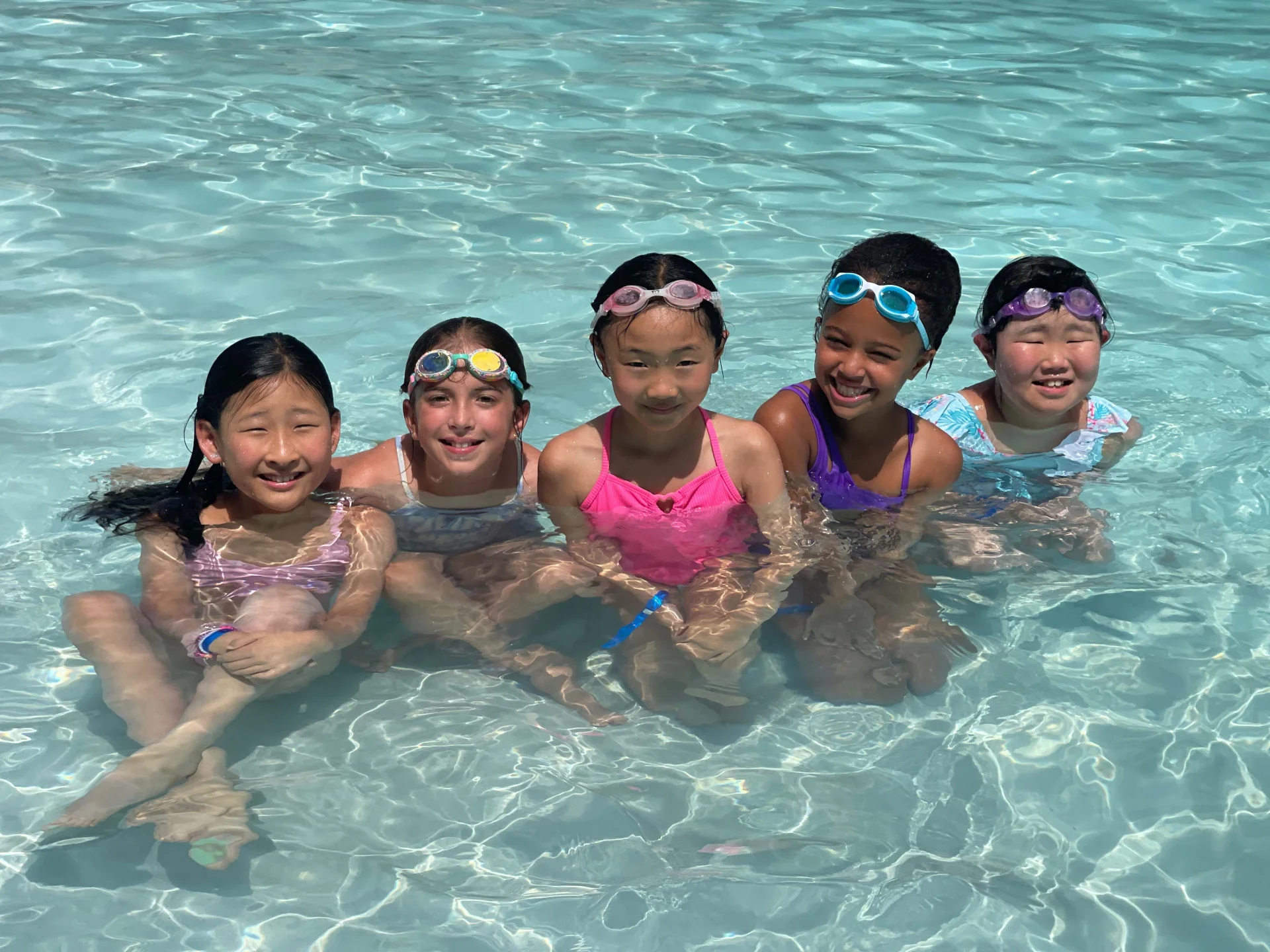 a group of girls in a pool at their swim camp
